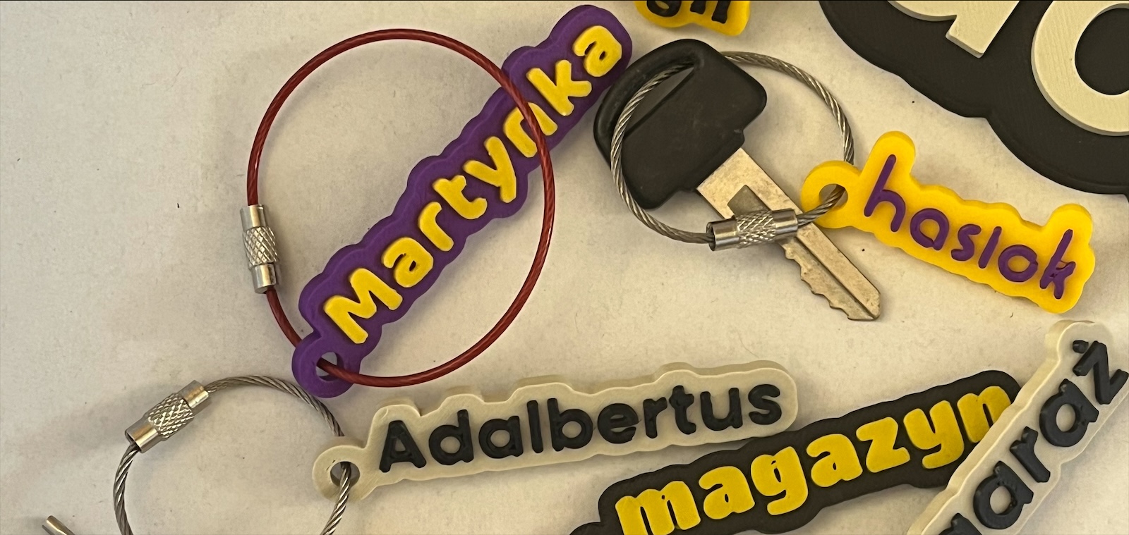 Stół w świetle dziennym: breloczki Martynka, haslok, Adalbertus, magazyn i garaż z linkami stalowymi
